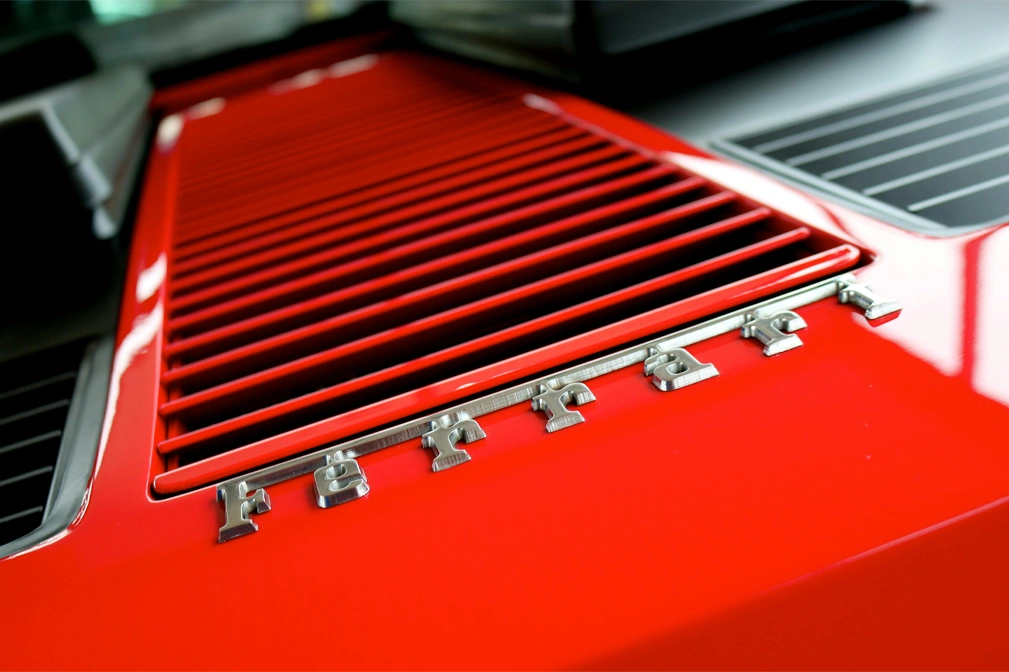Rear engine cover of a red Ferrari with chrome 'Ferrari' lettering
